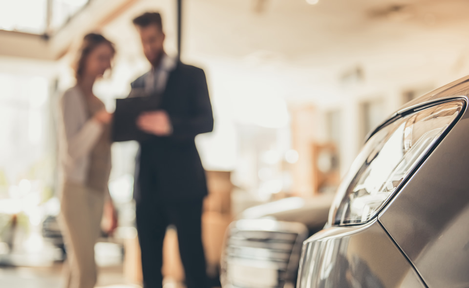 Two people discussing a car in a showroom